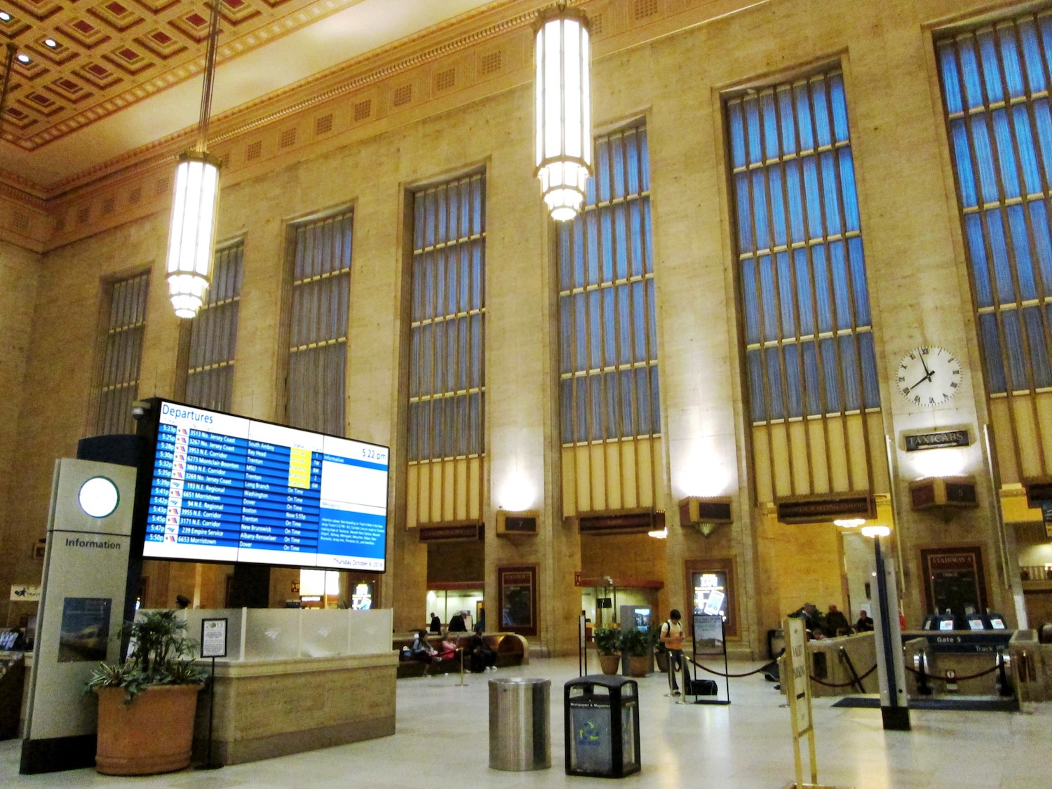 A mockup of 30th Street Station with a digital screen similar to that of Penn Station. The sign is bright and out of place in the historic stone building.